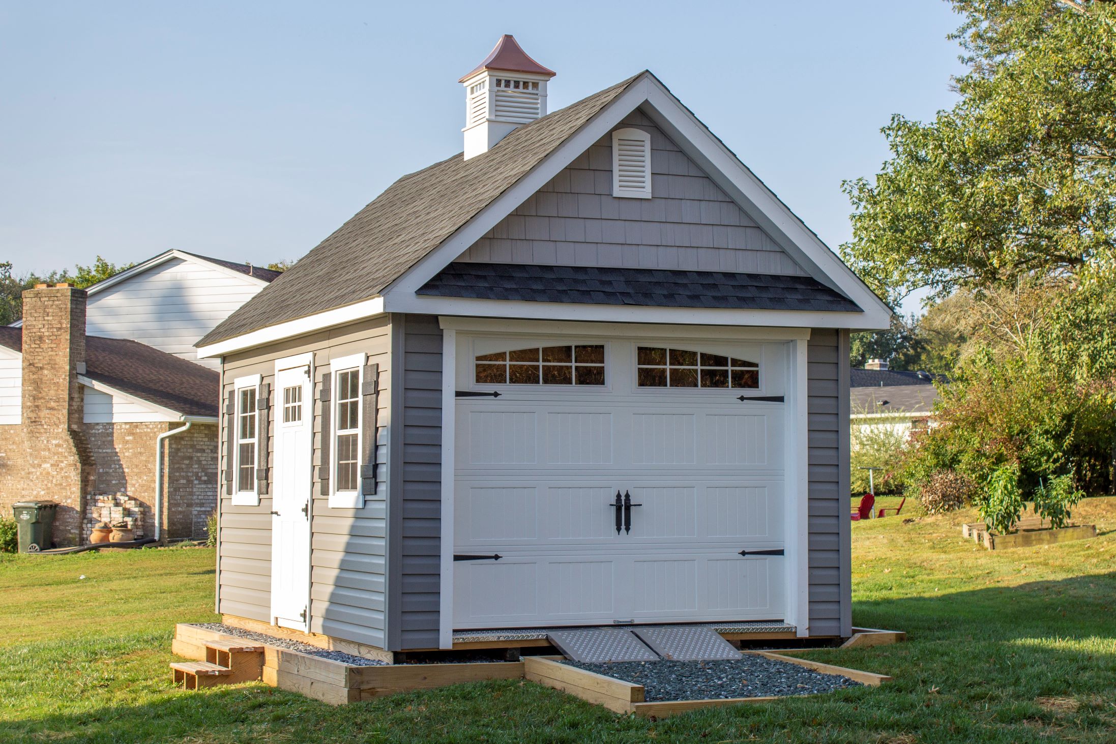 Exterior of a New England Barn Shed with gray siding and a white barn door.