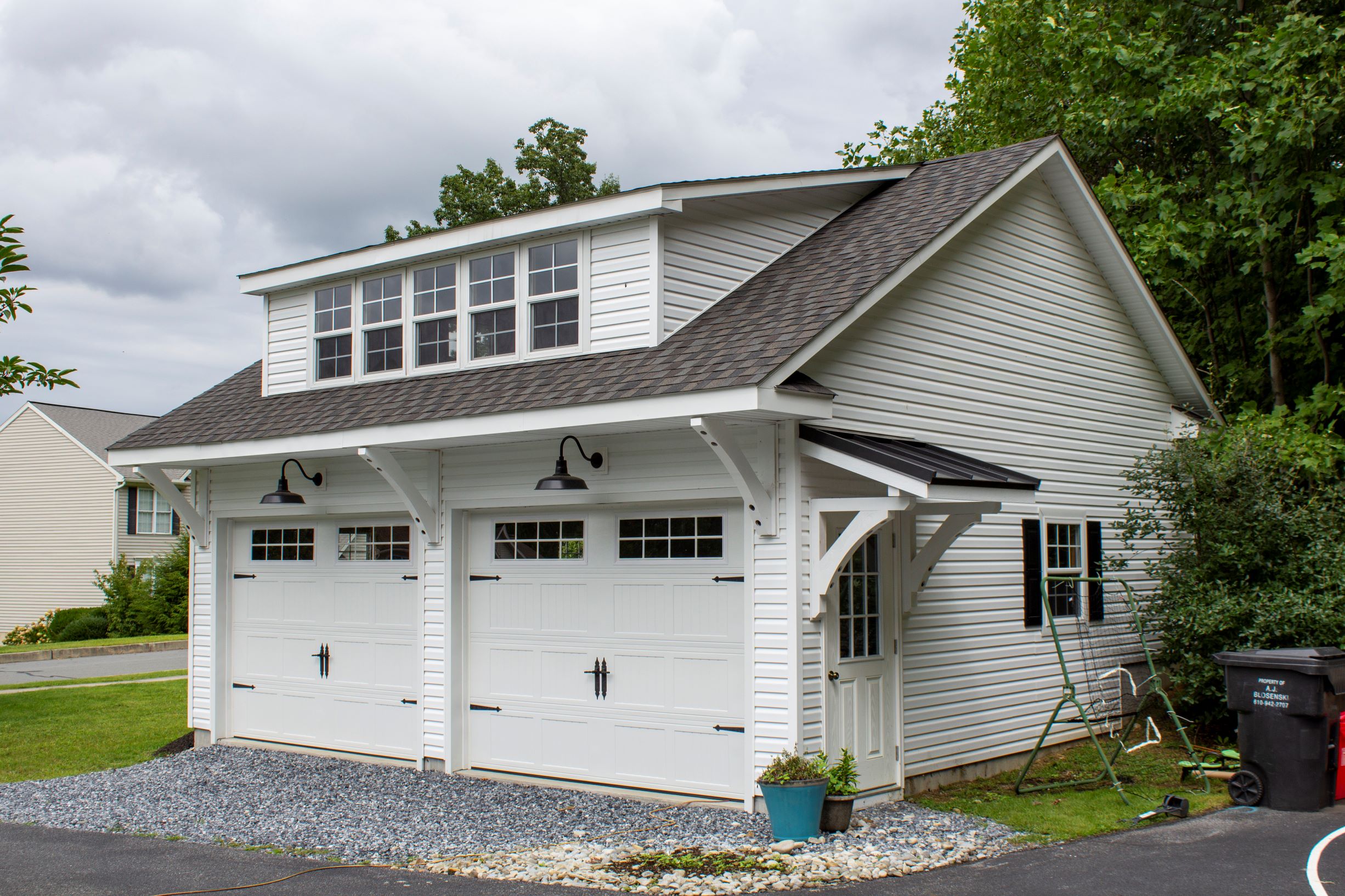 Exterior of a 2-story, 2-car Garden Shed Garage with white siding and white garage doors.
