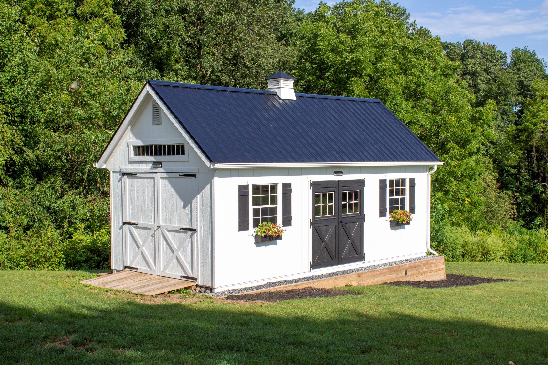 Front and side exterior of a New England Barn Shed with white siding.