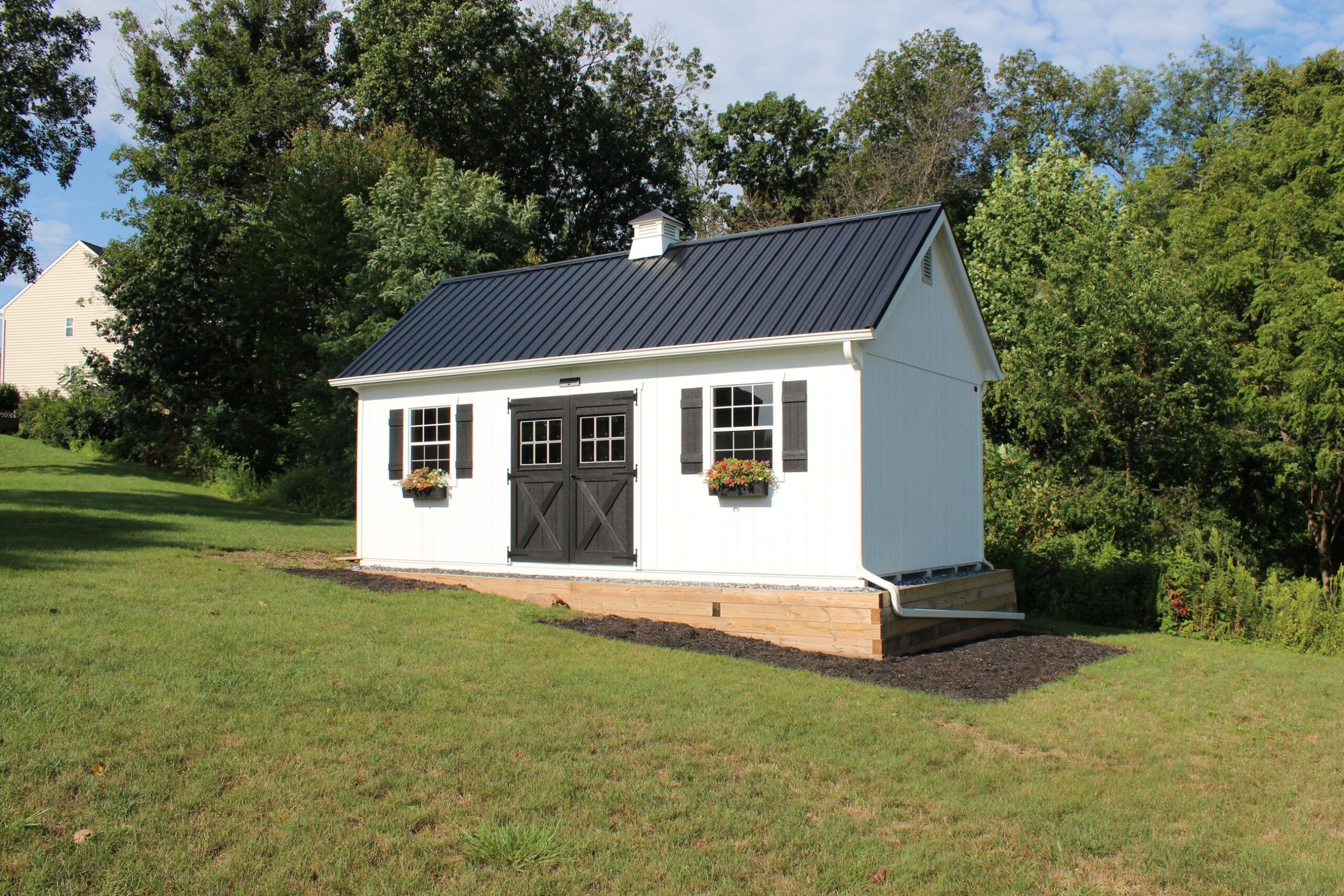 Front and side exterior of a New England Barn Shed with white siding.
