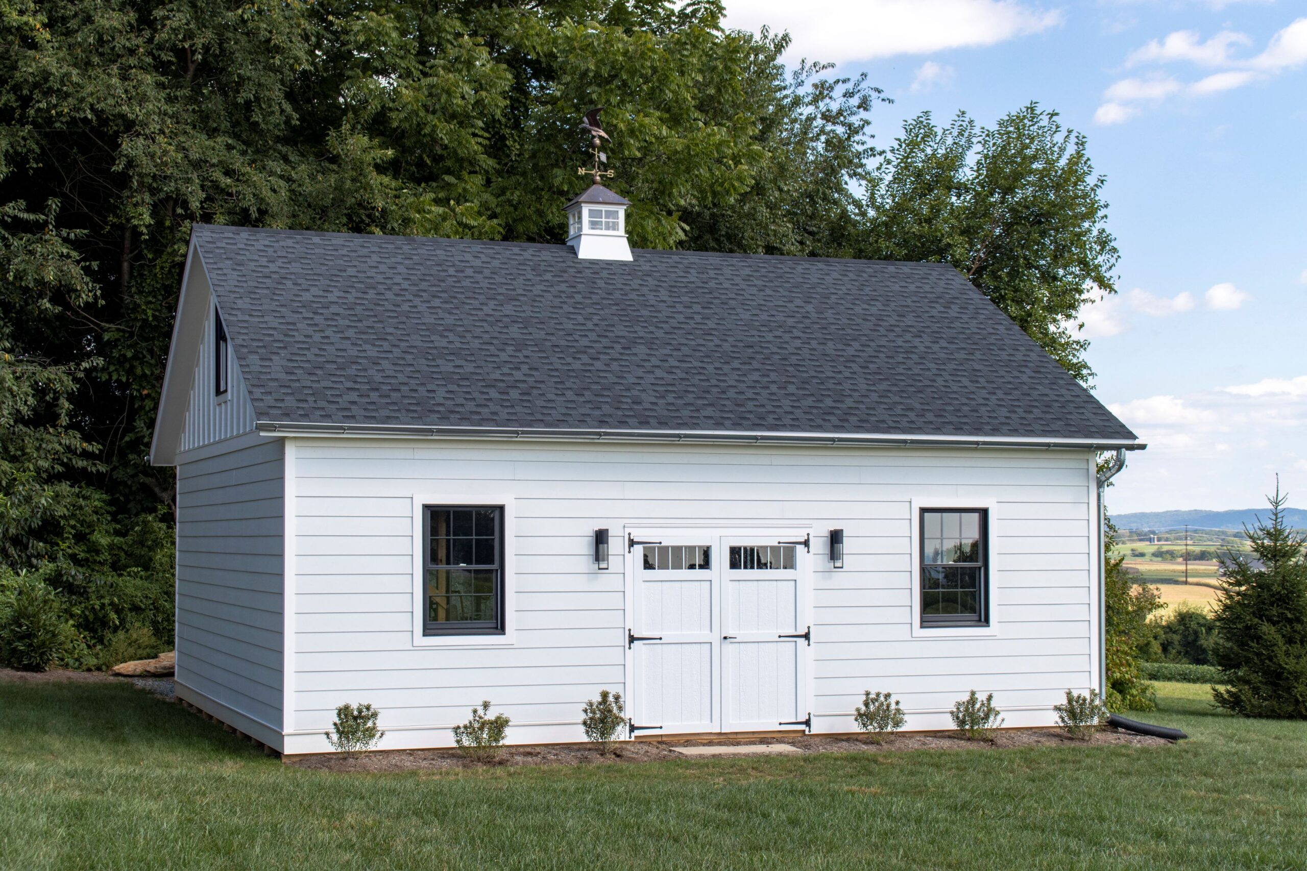 Exterior of a 2-story, 2-car Garden Shed Garage with white siding and gray roofing.