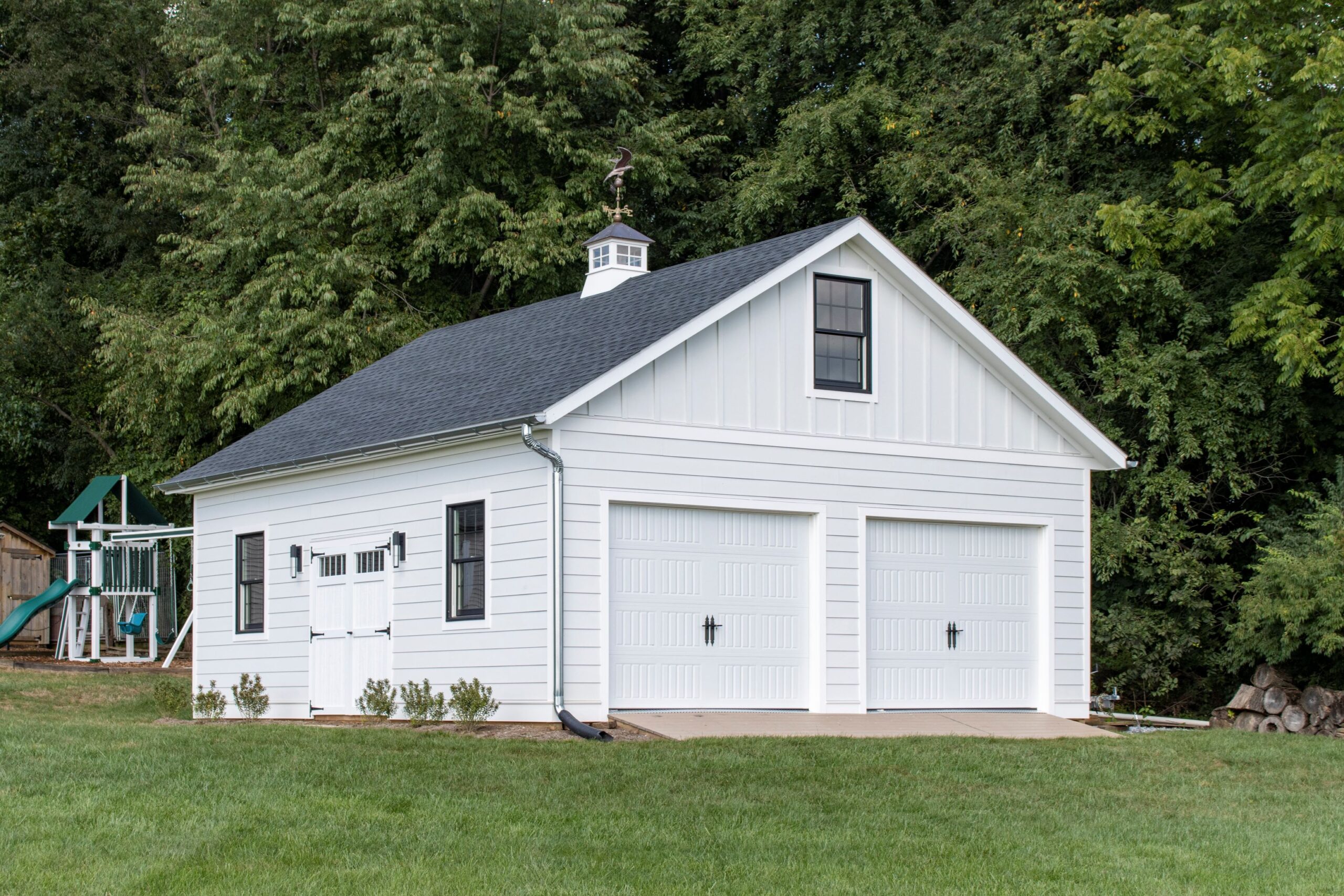 Exterior of a 2-story, 2-car Garden Shed Garage with white siding, gray roofing, and white garage doors.