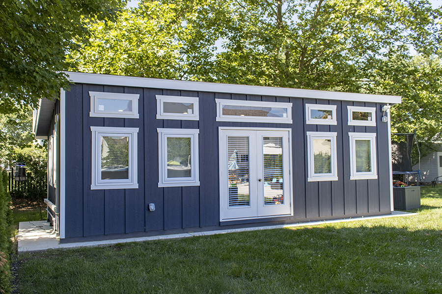 Front exterior of a Studio Shed with blue siding and white trim.