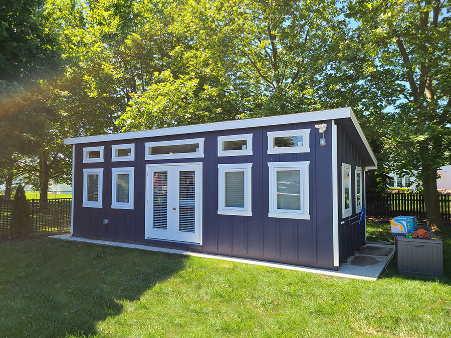 Front exterior of a Studio Shed with blue siding and white trim.