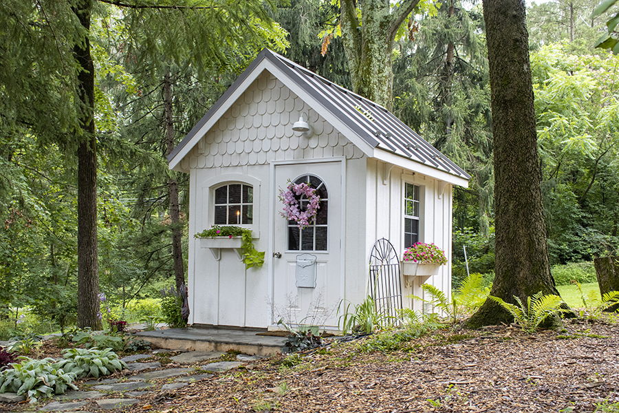 Front exterior of a small Garden Shed with white siding and gray roofing.