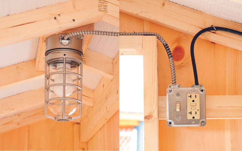Ceiling light with a cage covering next to an outlet with a light switch.