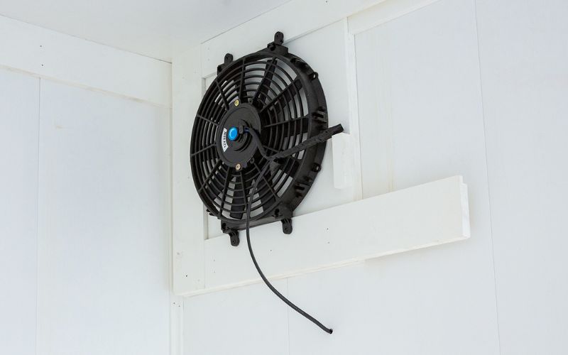Close up of a black 12-volt exhaust fan in a dog kennel