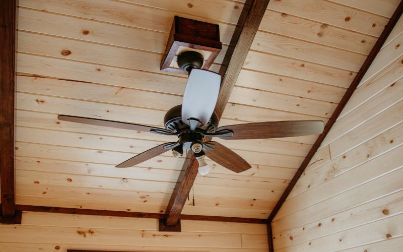 Close up of a brown and black wood ceiling fan in an cabin