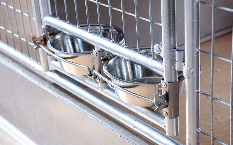 Close up of 2 mounted stainless dog bowls in a dog kennel