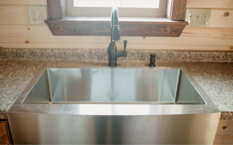 Close up of a stainless steel farmhouse sink in a kitchen
