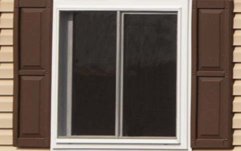 Close up of a white window with brown vinyl raised shutters
