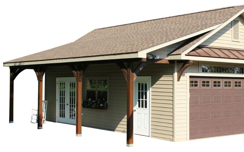 Garage shed with tan vinyl siding and a cape cod overhang with brown posts