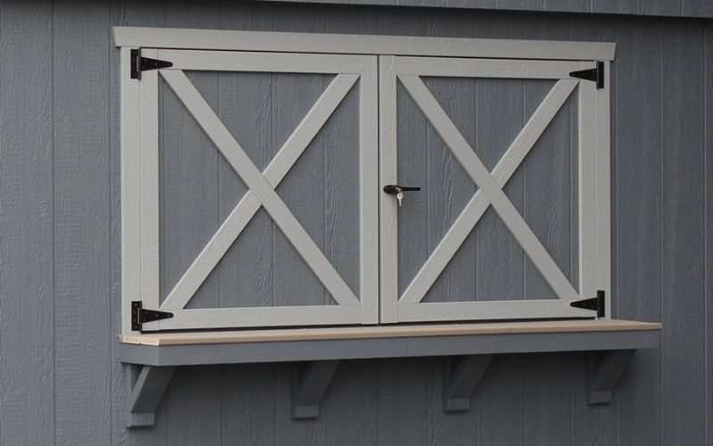 Close up of a wood gray swing out concession door with white trim