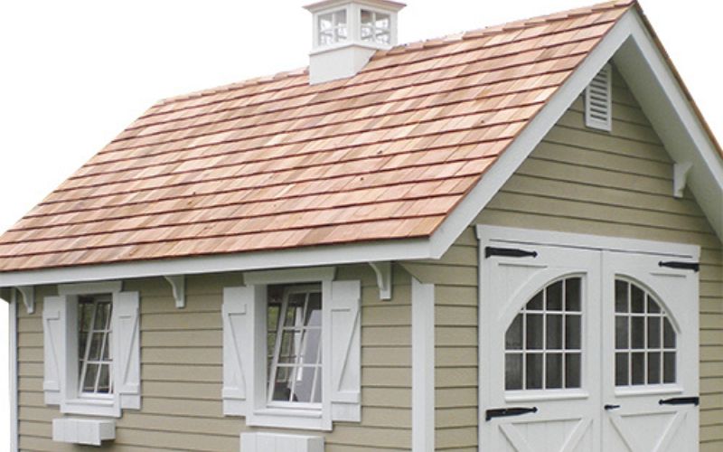 Decorative roof braces in white on a tan shed with white trim