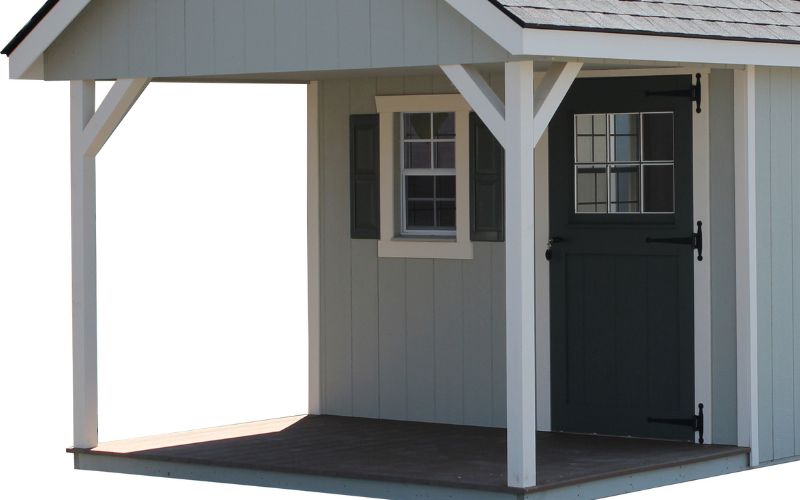 A covered end porch with white posts on a building with gray siding