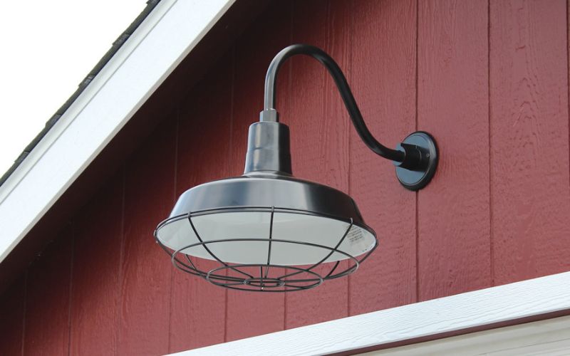 Close up of a black exterior overhead pan light attached to the top of a red and white building