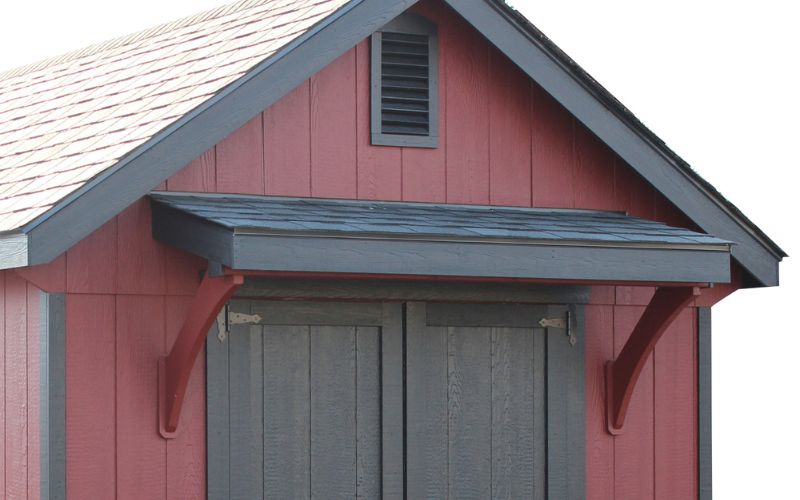 Close up of a black gable door overhang installed on a red and black shed