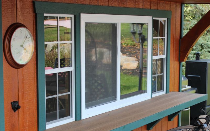 Insulated sliding concession window in white with green trim and a brown counter