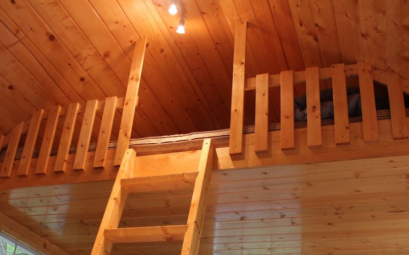 Close up of a shed loft with a wood ladder and wood railing