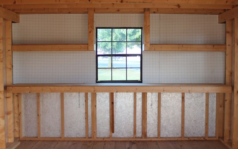 Shed interior with a bench, pegboard, and black window