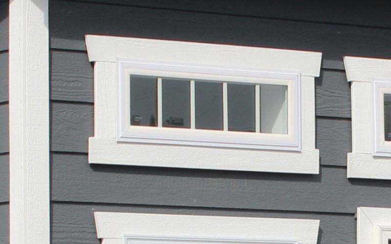 Close up of a short vinyl insulated transom window in white with white wood trim