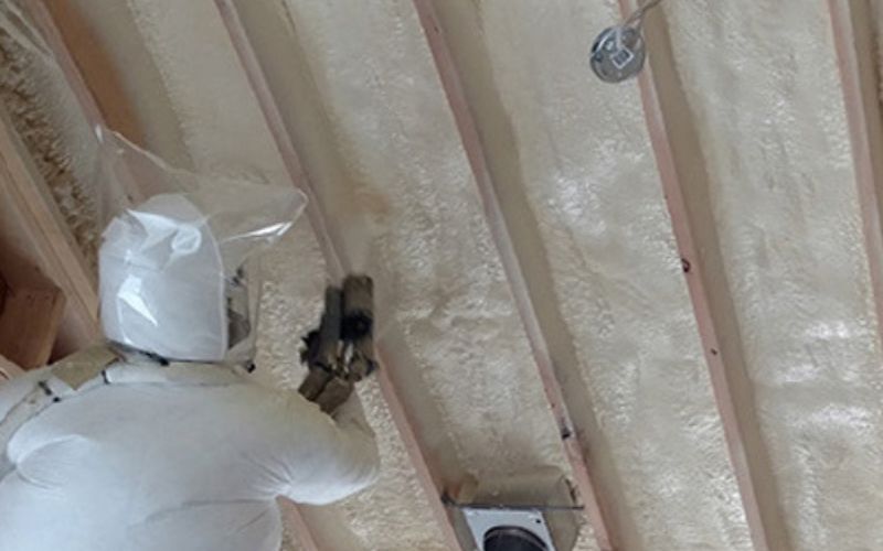 Person applying spray foam insulation to building walls