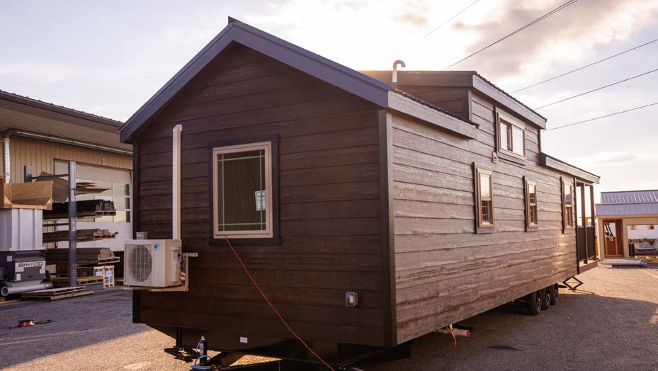 Back view of an Appalachian Park Model with dark stained wood siding, white windows, and metal roofing.