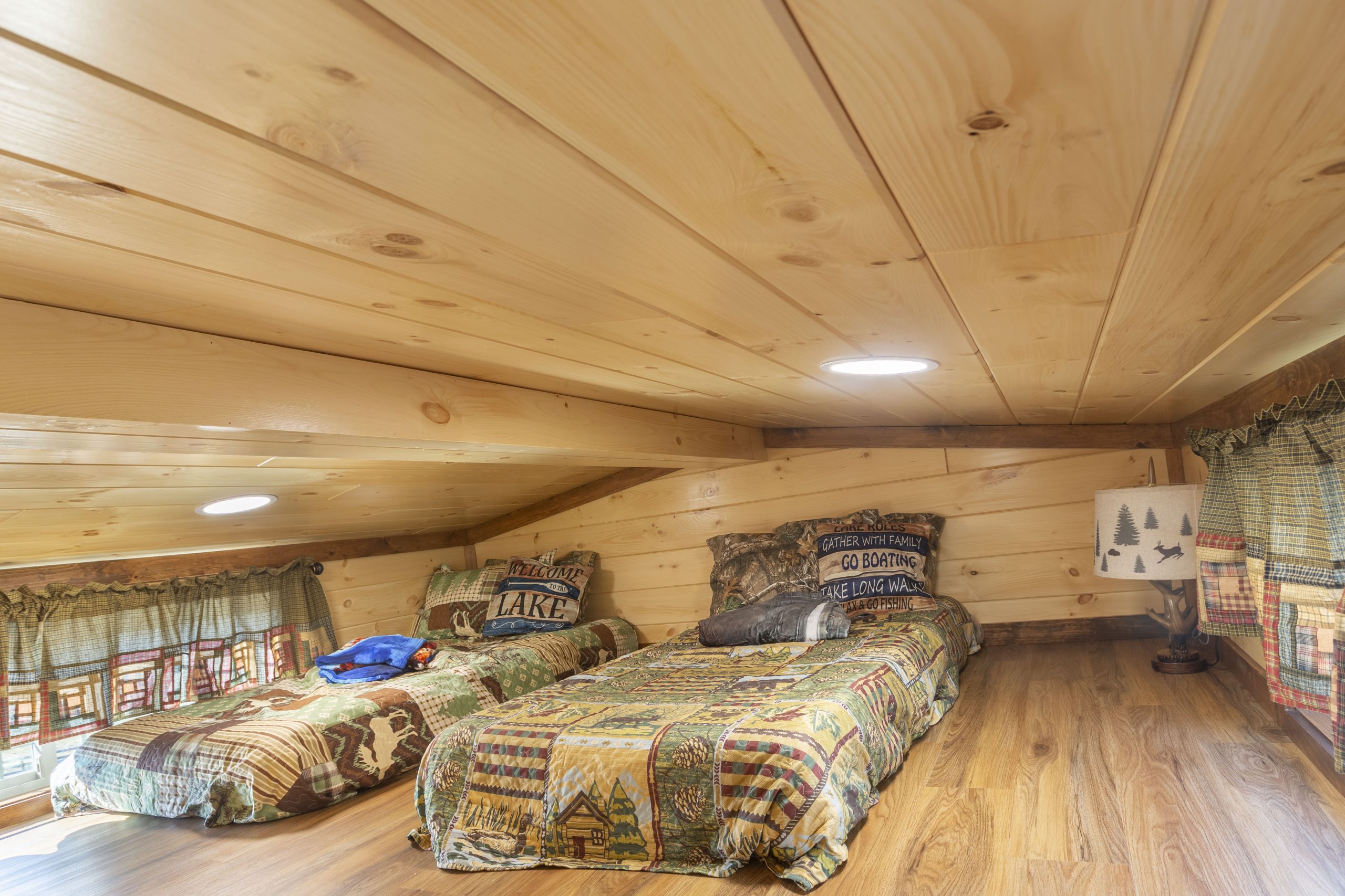 Close up of a loft bedroom in an Appalachian Park Model with 2 beds, natural wood walls, and natural decor.