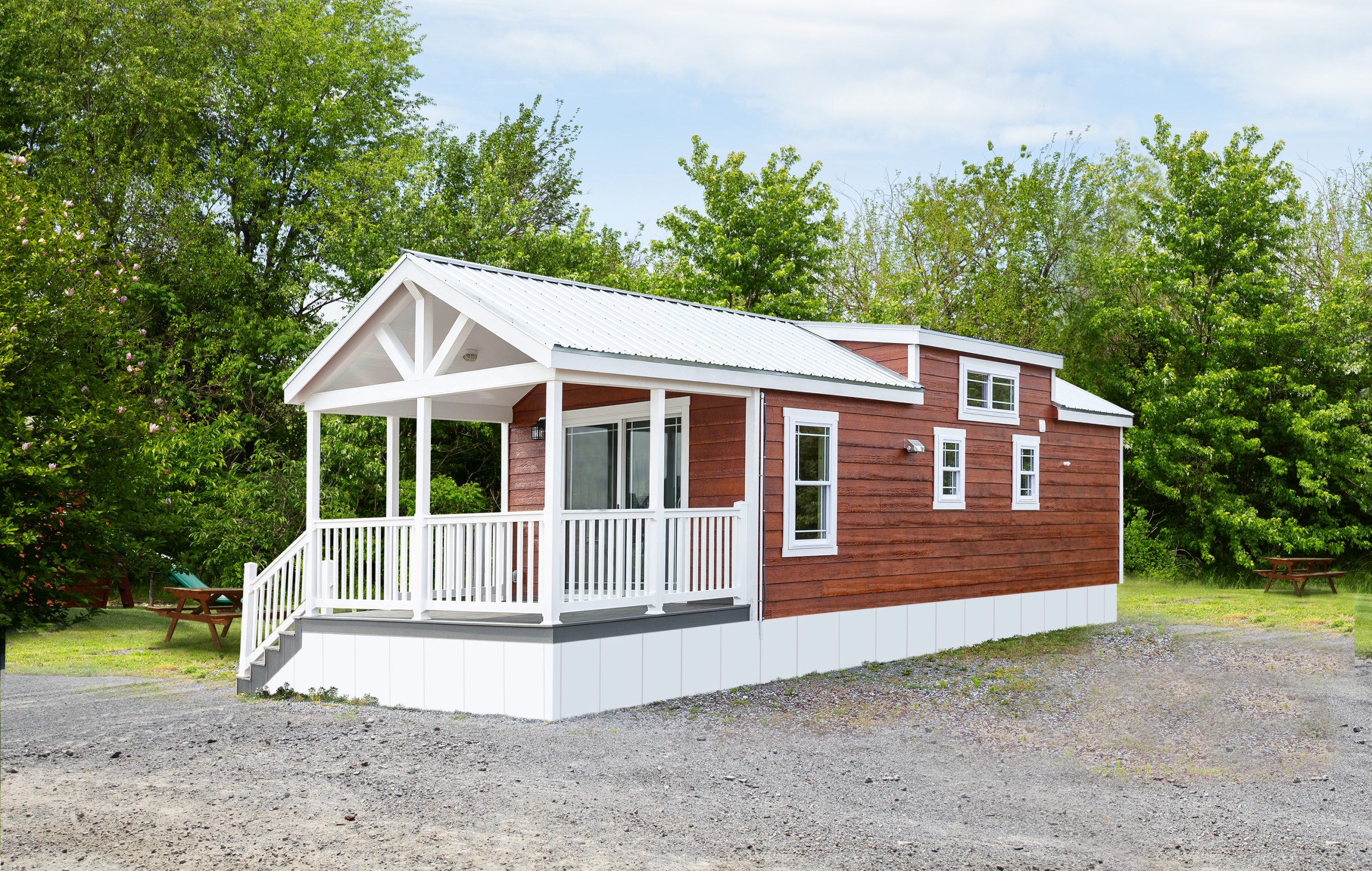 Front exterior view of an Appalachian Park Model with stained wood siding, white trim, white windows, and a white covered front porch.