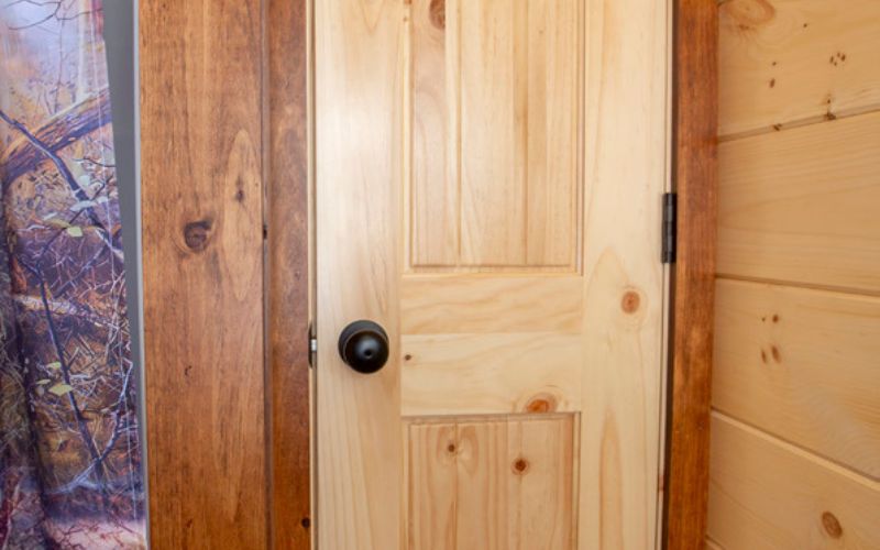 Close up of a natural wood door leading to a bathroom closet.