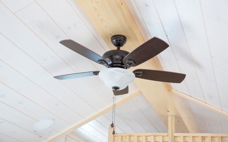 Close up of a dark brown and black ceiling fan in a park model.