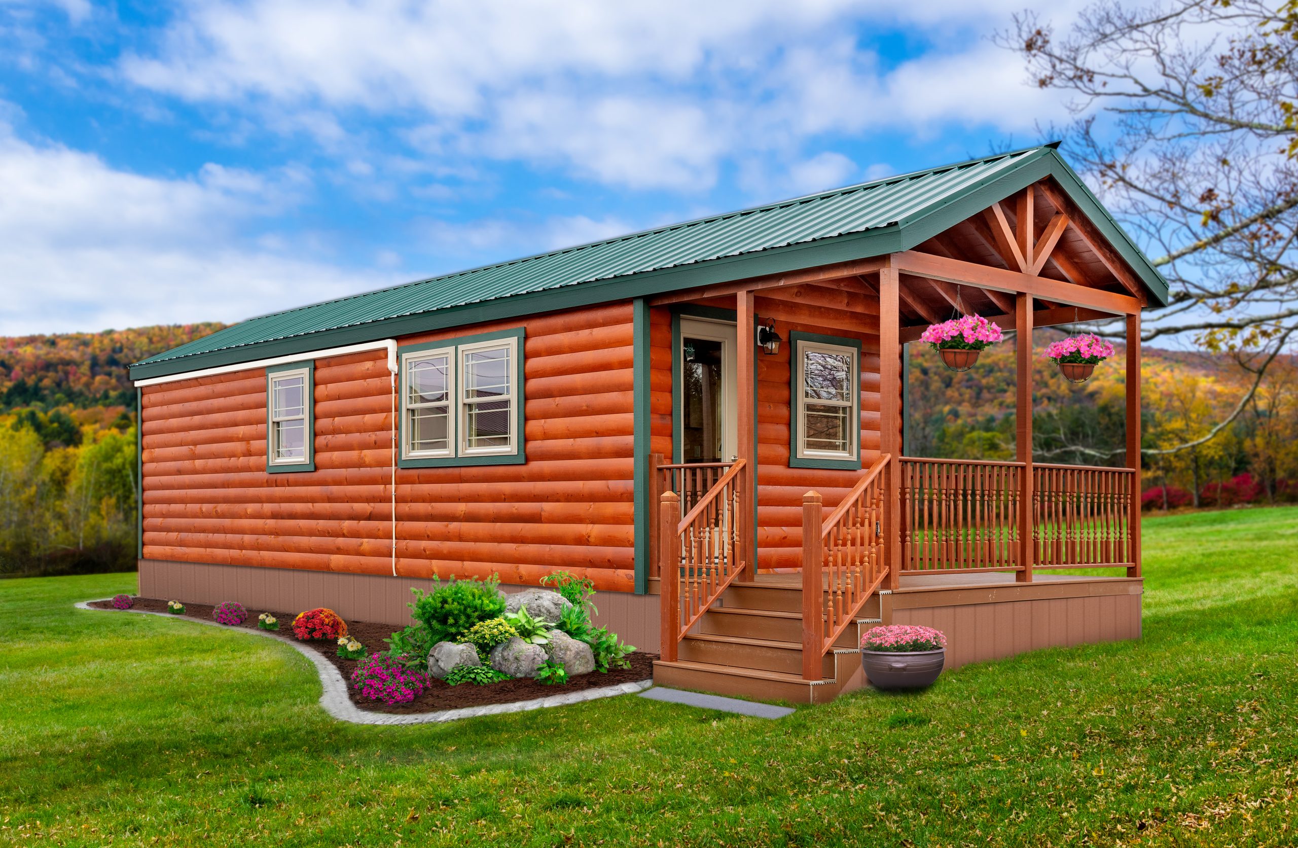 Front exterior of a Lake Port Park Model with stained log siding, green trim, a green metal roof, green and white windows, and a fenced-in front porch with a single glass door entrance.