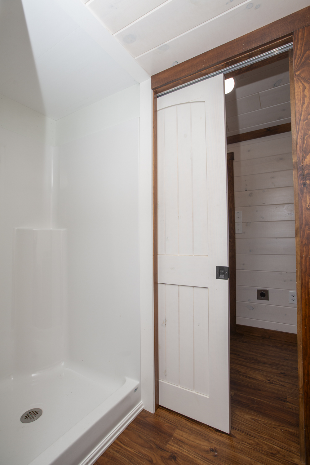 Close up of a white pocket door in a bathroom next to a shower.