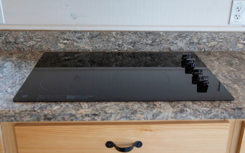 Close up of a smooth surface stove in a kitchen with laminate countertops.