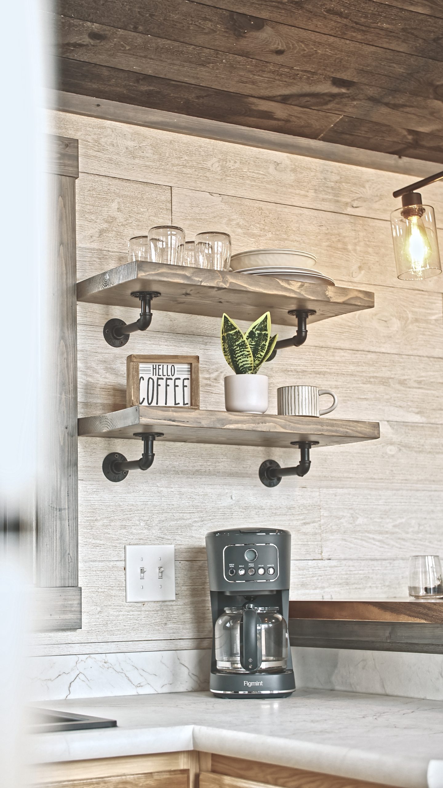 Close up of details in a Meadowlark Park Model kitchen with open shelves, light wood cabinets, a coffee maker, and white countertops.