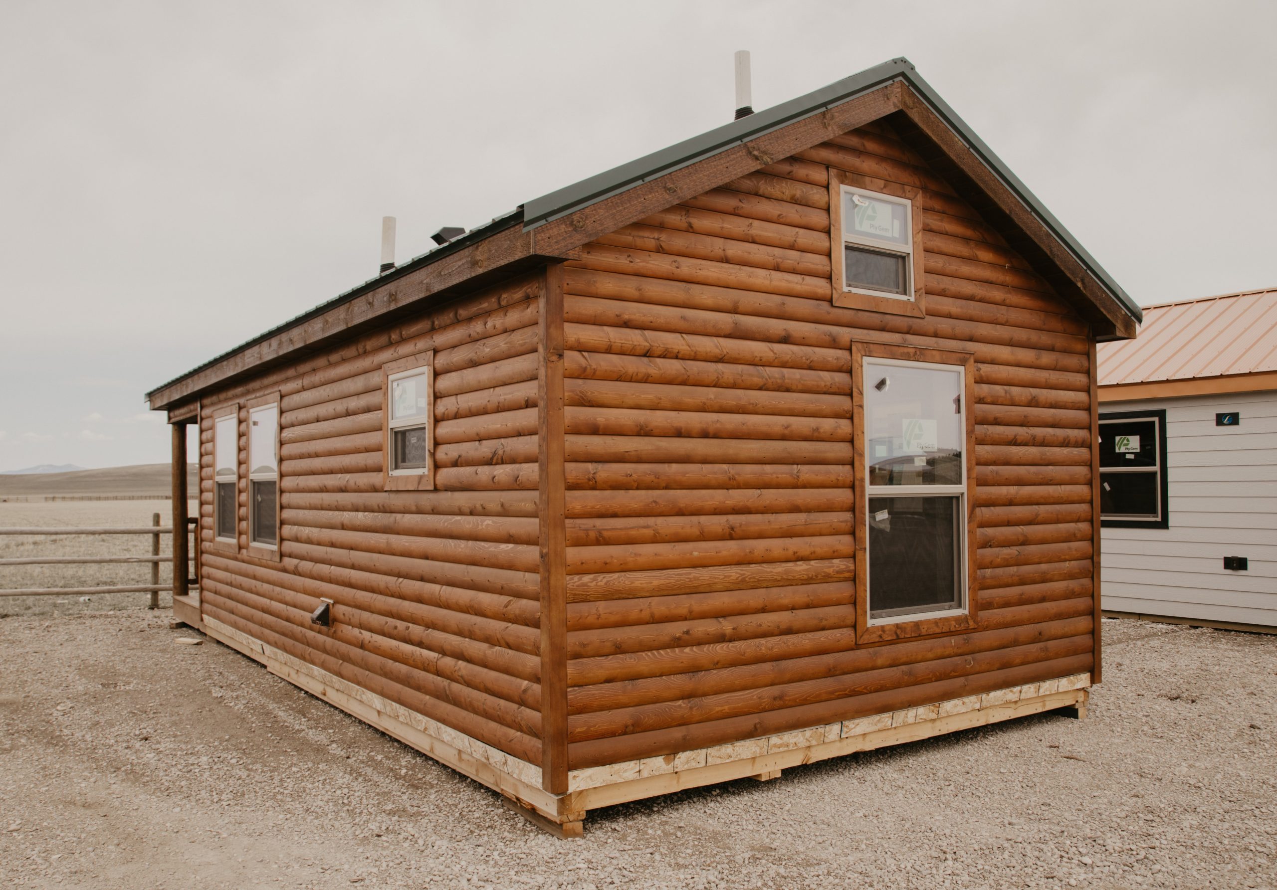 Back and side exterior of a 14x30 tiny home with log wood siding, black metal roofing, and white windows.