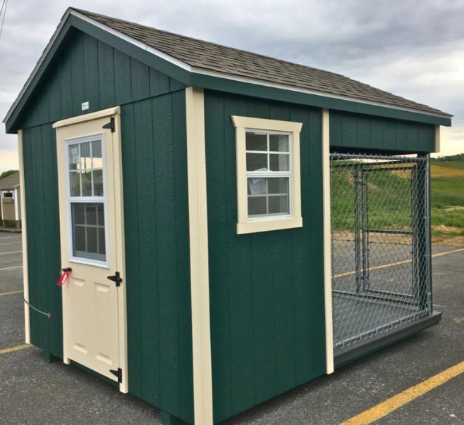 Back view of a 8x10 dog kennel with green siding, beige trim, a single-entry door with windows, a white window, a dog run with chain link fencing, and gray asphalt roofing.