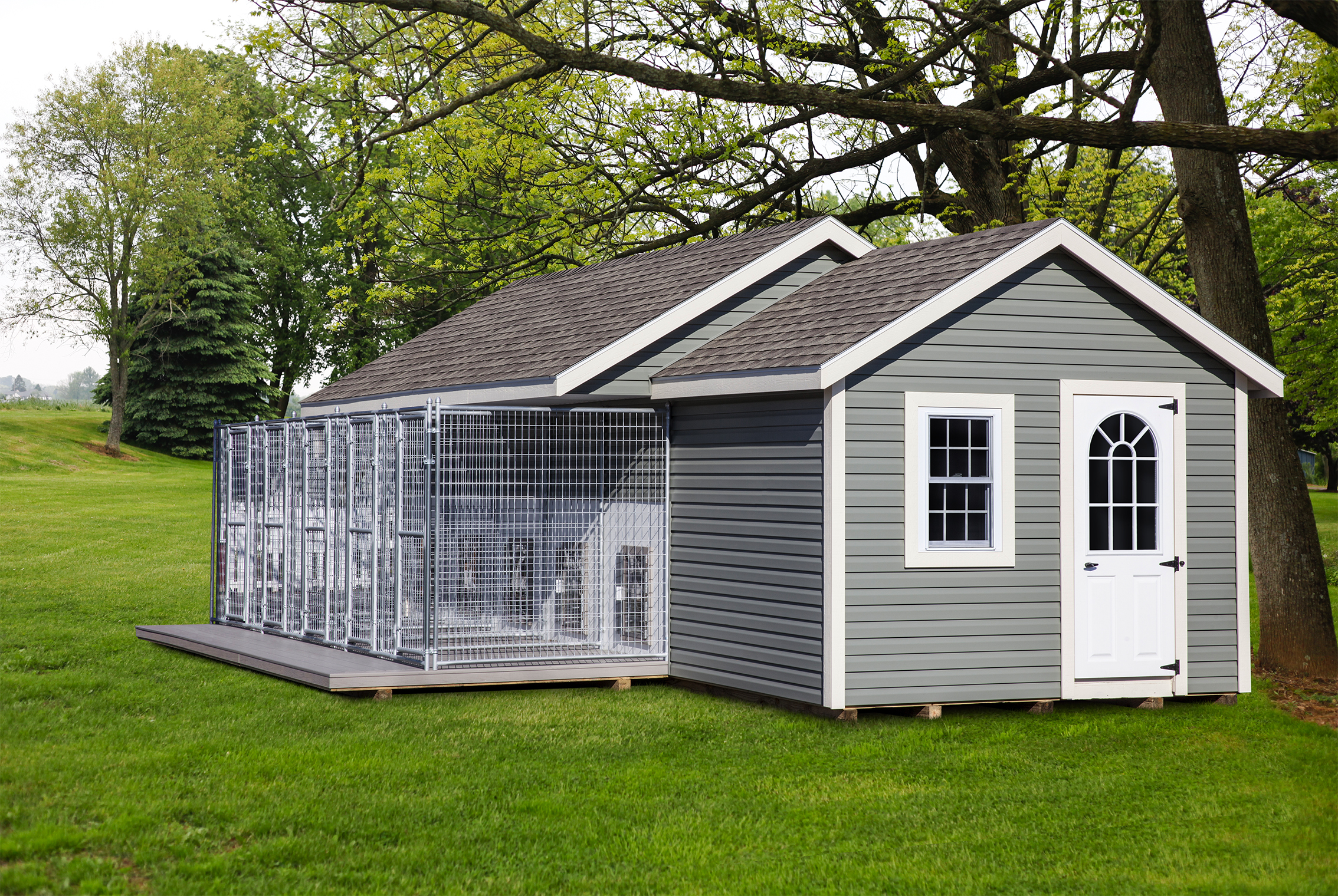 10x28 dog kennel with gray siding, white trim, a white single-entry door with arched windows, a white window, a brown asphalt roof, and 5 dog boxes.